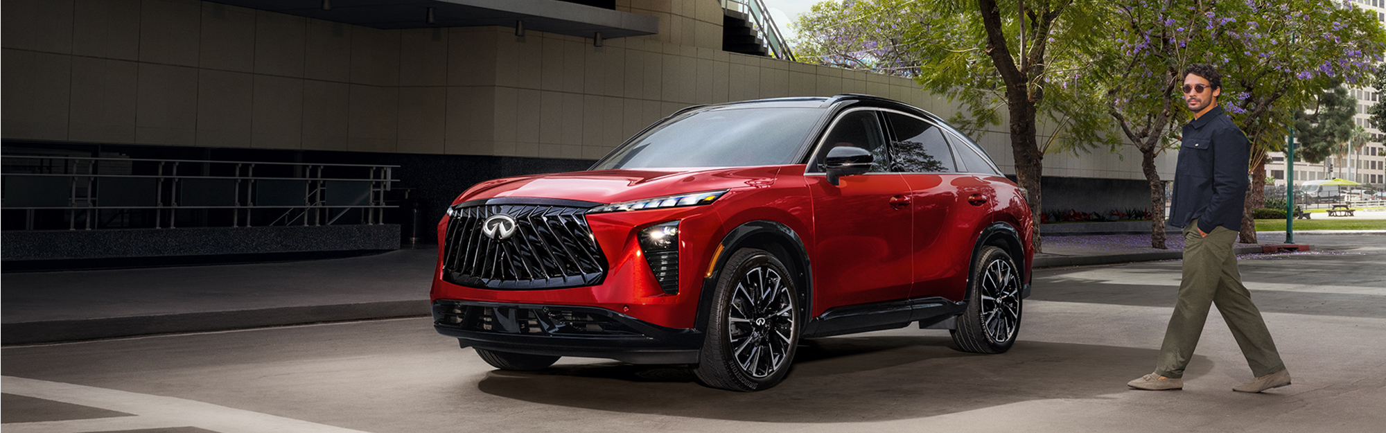 2027 Infiniti QX65 in red parked on a city street, showcasing its bold grille, sleek LED headlights, black wheels, and modern luxury SUV styling.
